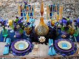 a super colorful tablescape done in purple and turquoise, bright gold touches, colored glasses and plates and lush florals