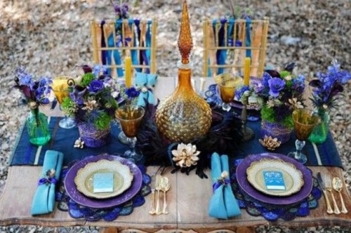 a super colorful tablescape done in purple and turquoise, bright gold touches, colored glasses and plates and lush florals