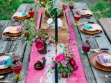 a super bright boho chic wedding tablescape with a tie dye table runner, antlers, colorful blooms and a terrarium plus bright cards