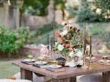 a low picnic table with candles, a lush floral centerpiece, books instead of placemats and vintage teacups