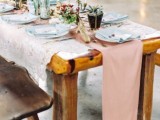 a boho tablescape with blush textiles, a lace tablecloth, greenery and blooms in planters and terrariums