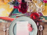 a colorful tablescape with bright textiles, colored plates and glasses and colorful florals