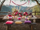 a bright boho tablescape with colorful pillows and florals, gilded touches, candle lanterns and garlands