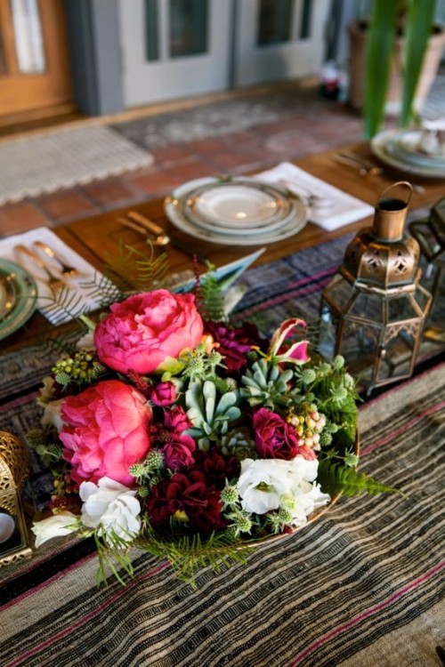 a folksy table runner, a bright floral centerpiece, Moroccan lanterns, printed plates