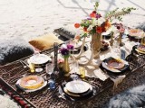 a picnic boho chic tablescape with a faux animal skin, antlers, bright florals and colored glasses and plates