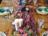 a bright table setting with a colorful floral table runner, floral print plates and emerald napkins plus candles