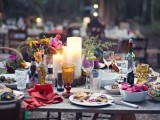 a bright boho table setting with colorful glasses, plates, chargers, napkins and florals
