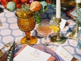 a colorful tablecloch, colorful glasses and plates, candles and super bright floral centerpieces
