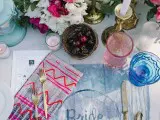 a bright table setting with colorful tie dye textiles, colored glasses and bright florals