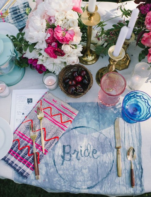 a bright table setting with colorful tie dye textiles, colored glasses and bright florals