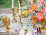 a lace table runner, colorful printed plates, colored glasses and super bright florals