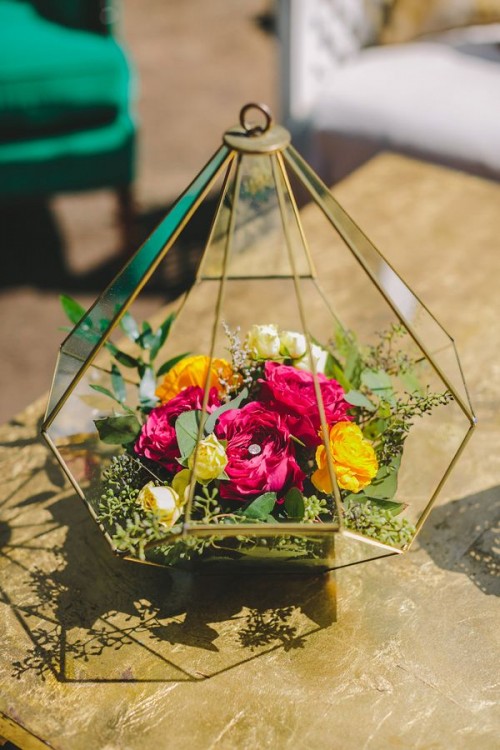 a terrarium wedding centerpiece with moss and bright fuchsia and yellow blooms is a nice centerpiece not only for a boho wedding