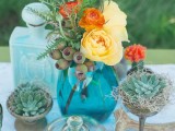 a turquoise vase with bright blooms, succulents, greenery and antlers for a woodland boho wedding