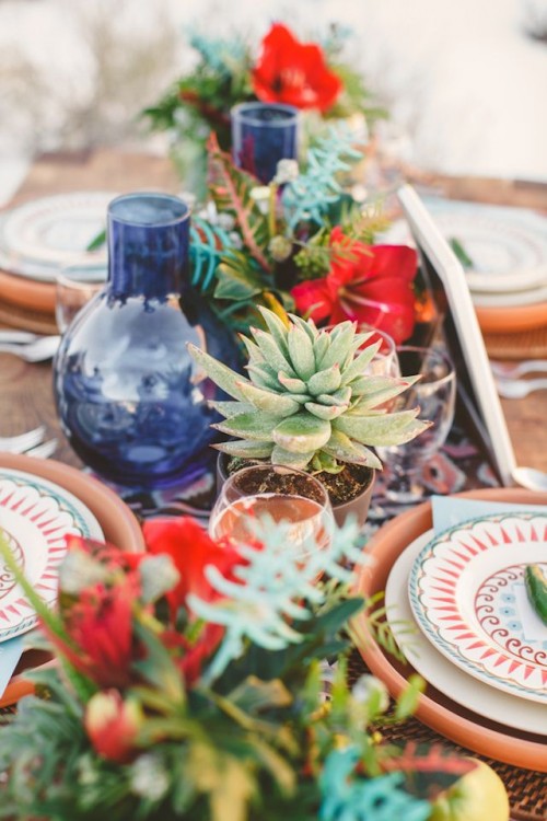 a bright red bloom centerpiece with greenery and succulents plus blue bottles is great for a bright boho wedding