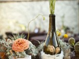 centerpieces of peachy blooms, pale greenery, a bottle with dried herbs and blooms
