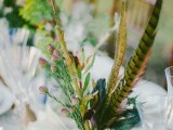 a boho wedding centerpiece of greenery and feathers is a creative boho wedding idea