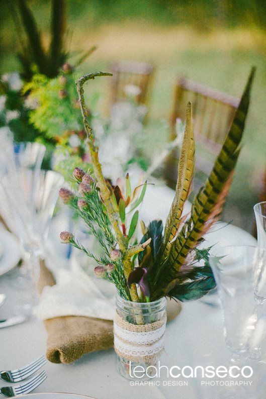 A boho wedding centerpiece of greenery and feathers is a creative boho wedding idea