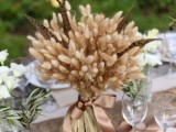 a wheat and feather wedding centerpiece will fit both a boho and a rustic wedding