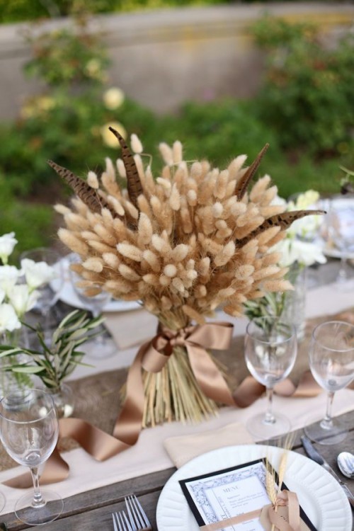 a wheat and feather wedding centerpiece will fit both a boho and a rustic wedding