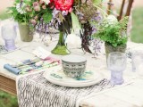 a bright and colorful floral wedding centerpiece with greenery in a green vase for a summer boho wedding