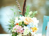 a colorful floral wedding centerpiece with greenery and feathers is amazing for a boho wedding