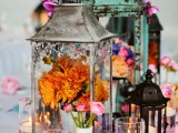 vintage candle lanterns with bright blooms in vases is a chic and creative idea for a Moroccan boho wedding