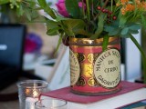 a tin can with bright blooms and foliage and candles will fit a boho or a backyard wedding easily