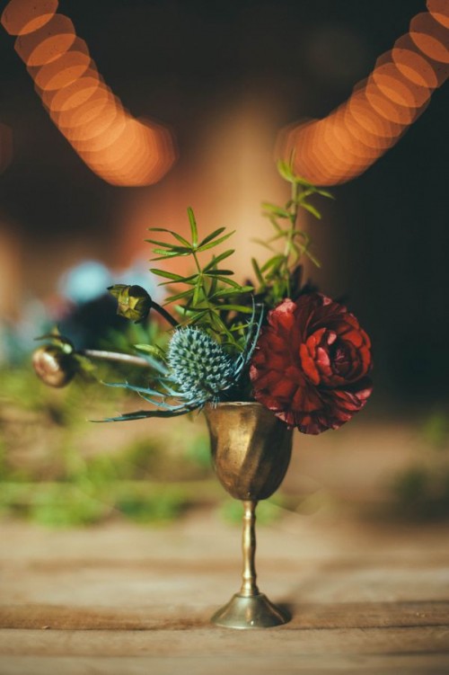 a gold goblet with bright blooms and thistles plus greenery for a vintage wedding with a boho feel