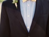 a black suit, a chambray shirt and a yellow bow tie plus a pastel floral boutonniere for a stylish look