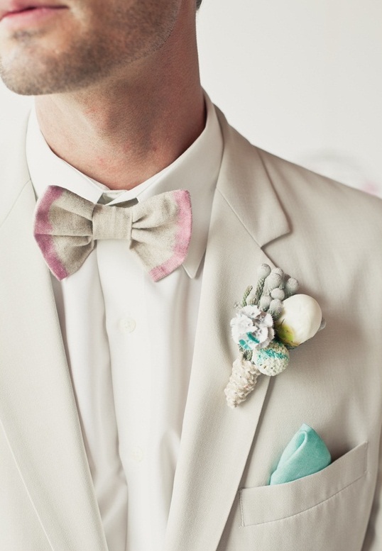 A neutral suit, a tie dye grey and pink bow tie and a snowy boutonniere for a chic and delicate groom's look