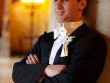a black tux with a white bow tie and a white floral boutonniere for a stylish and elegant groom’s look