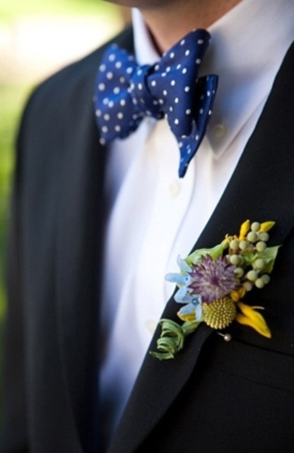 a black suit, a navy polka dot bow tie and a colorful floral boutonniere for a bold summer groom's look