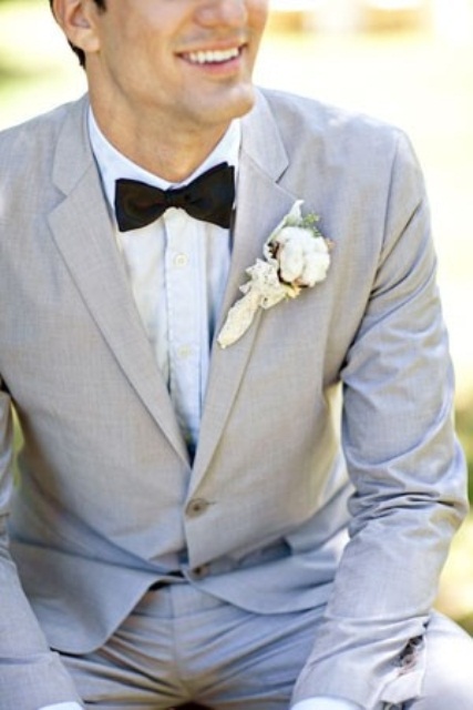 a light grey suit, a white shirt and a black bow tie plus a cotton boutonniere is an elegant and stylish groom's look