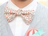 a bright seaside groom’s look with a white shirt, a navy and white striped waistcoat, a colorful printed bow tie and boutonniere