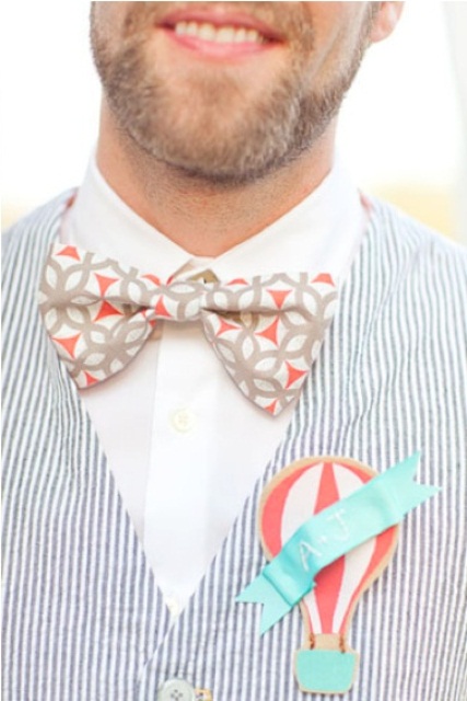 a bright seaside groom's look with a white shirt, a navy and white striped waistcoat, a colorful printed bow tie and boutonniere