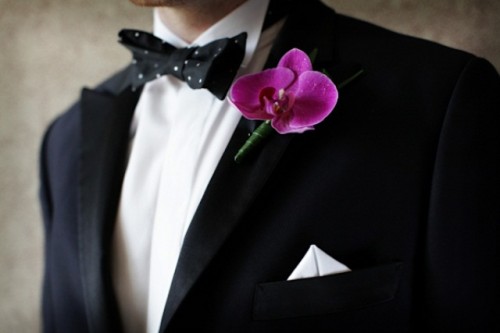 a black tux, a black and white polka dot bow tie and a pink orchid boutonniere for a luxurious and refined groom's outfit