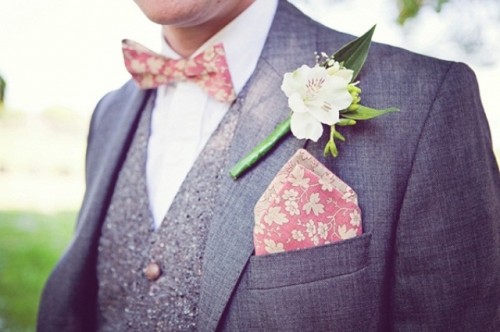 a coral botanical print bow tie and handkerchief and a fresh white bloom accent the outfit in a chic and cool way