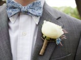 a grey suit, a white shirt and a blue printed bow tie and a white bloom boutonniere for an elegant and stylish spring groom’s look
