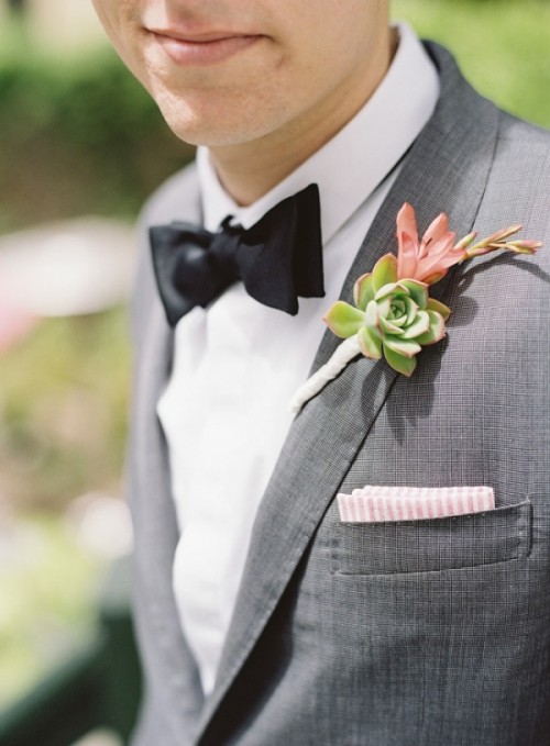 a grey suit, a white shirt, a black bow tie and a succulent boutonniere for an elegant spring or summer groom's look