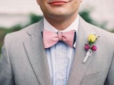 a light grey suit, a blue shirt, a pink bow tie and a colorful floral boutonniere for a bright summer look