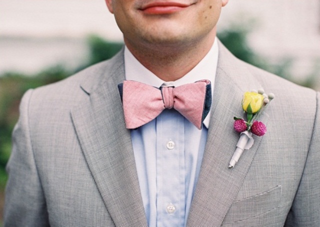 A light grey suit, a blue shirt, a pink bow tie and a colorful floral boutonniere for a bright summer look