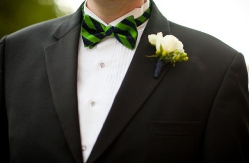 a cheerful green and black striped bow tie and a white bloom boutonniere make the outfit catchy and cool