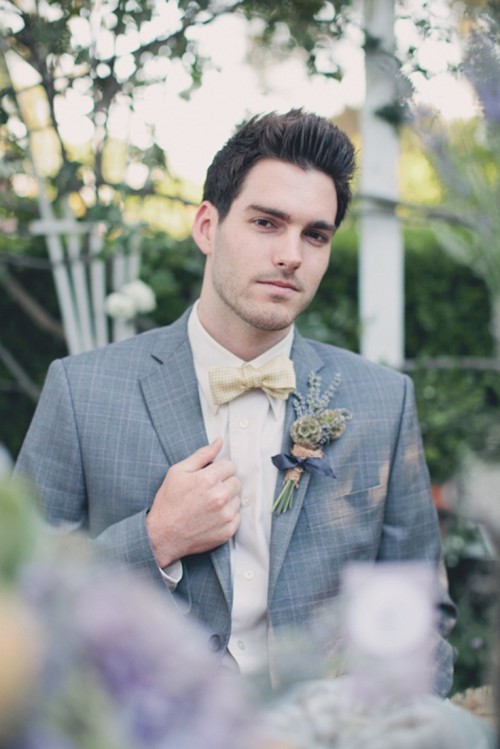 a plaid grey suit, an ivory shirt and a plaid yellow bow tie plus a floral boutonniere