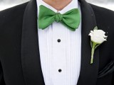 a black tux, a white shirt with black buttons, an apple green bow tie and a neutral floral boutonniere for an elegant and refined look