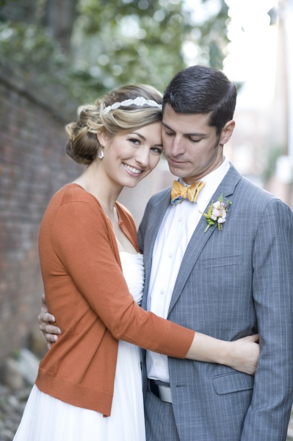 A striped gold bow tie and a pastel floral boutonniere accent the grey suit and add chic to it