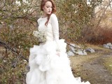 a bride rocking a beautiful wedding ballgown with a train and a white cable knit sweater on top to take some pics outside without getting cold