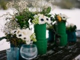 a bold winter wedding centerpiece of vases with green cable knit cozies, white anemones and baby’s breath is a great idea