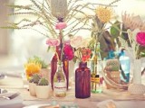 a creative cluster wedding centerpiece of various bottles and vases, blooms, succulents and cacti for a bold look