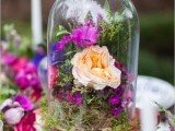 a garden bridal shower tablescape with a stack of books, moss with bright blooms in a cloche is a chic and refined idea