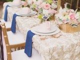 a pretty garden bridal shower table with a fabric flower tablecloth, pretty neutral and pastel florals, fresh blooms hanging from above
